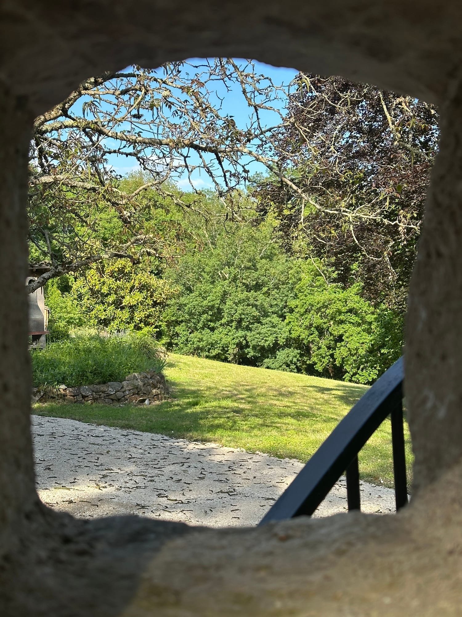 Le jardin vu à travers une ouverture dans le mur de pierre