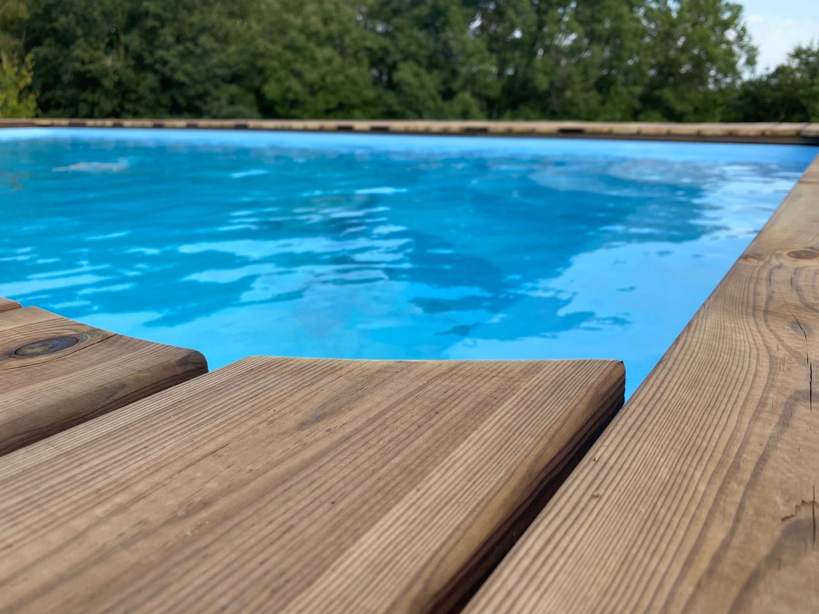 L’eau turquoise de la piscine au bord de la terrasse en bois