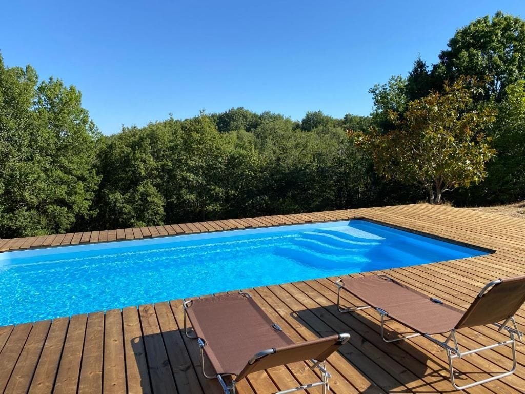 La piscine, sa terrasse en bois et deux transats face à la forêt