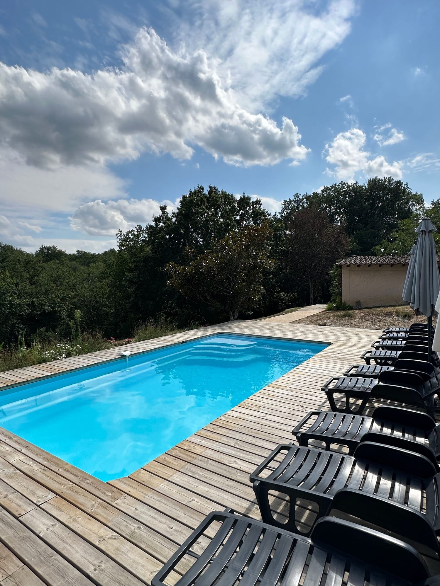 La piscine et ses transats sous un ciel de nuages